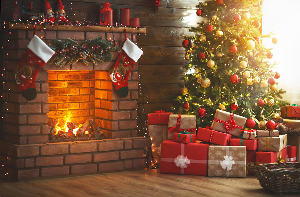 fireplace with stockings on it next to a christmas tree with presents